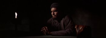 Movie still from “The Greatest Story Ever Told” (1965), directed by David Lean – A man in a dark room with his hands clasped together; Close Up shot, Low angle