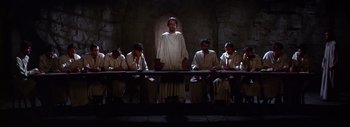 Movie still from “The Greatest Story Ever Told” (1965), directed by David Lean – A group of people sitting around a table; Wide shot, Low angle