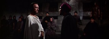 Movie still from “The Greatest Story Ever Told” (1965), directed by David Lean – A group of men standing next to each other in a dark room; Medium shot, Over the shoulder angle