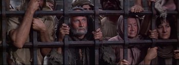 Movie still from “The Greatest Story Ever Told” (1965), directed by David Lean – An old man with a beard and a beard in a cage; Medium shot, High angle