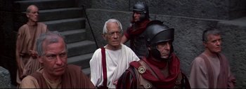 Movie still from “The Greatest Story Ever Told” (1965), directed by David Lean – An older man in roman garb is standing in front of a group of men; Medium shot, Over the shoulder angle