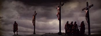 Movie still from “The Greatest Story Ever Told” (1965), directed by David Lean – A couple of people that are hanging from a cross; Wide shot, Low angle
