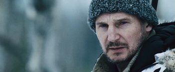 Movie still from “The Grey” (2011), directed by Joe Carnahan – A person wearing a jacket and a hat; Close Up shot, Low angle