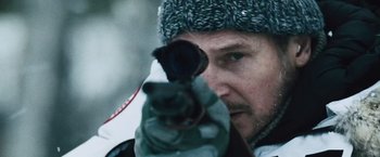 Movie still from “The Grey” (2011), directed by Joe Carnahan – A man in a hat is holding a gun; Close Up shot, Low angle