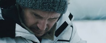 Movie still from “The Grey” (2011), directed by Joe Carnahan – A person wearing a jacket and a hat; Close Up shot, Over the shoulder angle