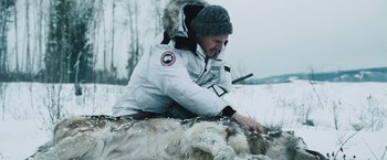 Movie still from “The Grey” (2011), directed by Joe Carnahan – A man kneeling down next to an animal in the snow; Medium shot, Low angle