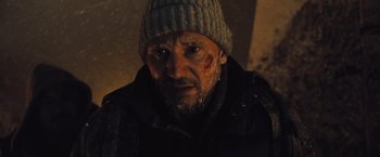 Movie still from “The Grey” (2011), directed by Joe Carnahan – A person wearing a jacket and a hat; Close Up shot, Low angle