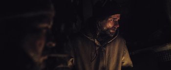 Movie still from “The Grey” (2011), directed by Joe Carnahan – A man with a beard wearing a hooded jacket; Close Up shot, Over the shoulder angle