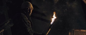 Movie still from “The Grey” (2011), directed by Joe Carnahan – A man holding a lit stick in the dark; Close Up shot, Low angle