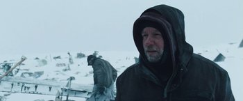 Movie still from “The Grey” (2011), directed by Joe Carnahan – A man in a hooded jacket standing in the snow; Close Up shot, Over the shoulder angle