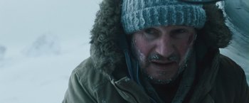 Movie still from “The Grey” (2011), directed by Joe Carnahan – A person wearing a jacket and a hat; Close Up shot, Over the shoulder angle