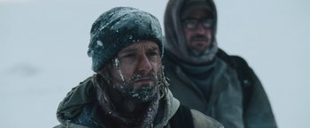Movie still from “The Grey” (2011), directed by Joe Carnahan – A man with a beard and a hat on; Close Up shot, Over the shoulder angle