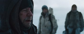 Movie still from “The Grey” (2011), directed by Joe Carnahan – A man with a beard is standing in the snow with another man; Close Up shot, Over the shoulder angle