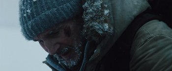 Movie still from “The Grey” (2011), directed by Joe Carnahan – A man with a beard and a hat is covered in snow; Close Up shot, Low angle
