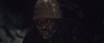Movie still from “The Grey” (2011), directed by Joe Carnahan – A person wearing a jacket and a hat; Close Up shot, Low angle