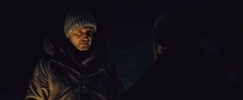 Movie still from “The Grey” (2011), directed by Joe Carnahan – A man wearing a hat and a jacket talking to another man; Close Up shot, Over the shoulder angle