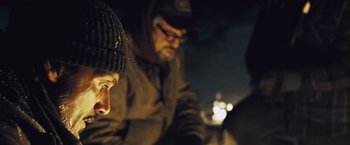 Movie still from “The Grey” (2011), directed by Joe Carnahan – A man and a woman sitting next to each other in the dark; Close Up shot, Over the shoulder angle