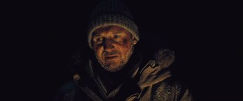 Movie still from “The Grey” (2011), directed by Joe Carnahan – A person wearing a jacket and a hat; Close Up shot, Low angle