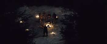 Movie still from “The Grey” (2011), directed by Joe Carnahan – A group of people standing around a fire in the middle of the night; Extreme Wide shot, High angle