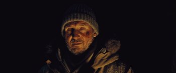 Movie still from “The Grey” (2011), directed by Joe Carnahan – A person wearing a jacket and a hat; Close Up shot, Low angle