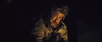 Movie still from “The Grey” (2011), directed by Joe Carnahan – A man in a brown jacket with a beard and messy hair; Close Up shot, Over the shoulder angle