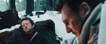 Movie still from “The Grey” (2011), directed by Joe Carnahan – Two people in the snow near a tree stump; Close Up shot, Over the shoulder angle