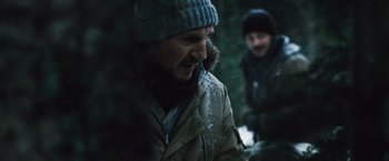 Movie still from “The Grey” (2011), directed by Joe Carnahan – A man wearing a winter coat and a hat is standing outside; Close Up shot, Over the shoulder angle