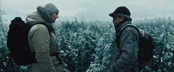 Movie still from “The Grey” (2011), directed by Joe Carnahan – Two people standing in front of a forest; Medium shot, Low angle