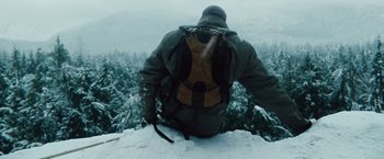 Movie still from “The Grey” (2011), directed by Joe Carnahan – A man with a backpack is sitting on a snowy hill; Medium shot, Low angle