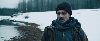 Movie still from “The Grey” (2011), directed by Joe Carnahan – A man in a hat and jacket standing in the snow; Close Up shot, Over the shoulder angle