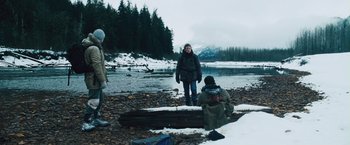 Movie still from “The Grey” (2011), directed by Joe Carnahan – A woman standing in the snow next to a log; Wide shot, Low angle
