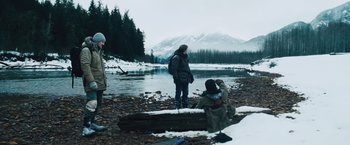 Movie still from “The Grey” (2011), directed by Joe Carnahan – Two people standing near a body of water; Wide shot, Low angle
