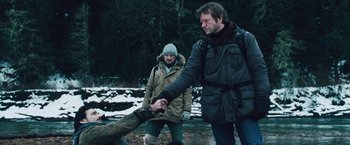 Movie still from “The Grey” (2011), directed by Joe Carnahan – Two men are holding hands in the snow; Medium shot, Over the shoulder angle