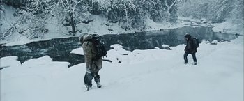 Movie still from “The Grey” (2011), directed by Joe Carnahan – A man with a backpack walking up a hill in the snow; Wide shot, High angle