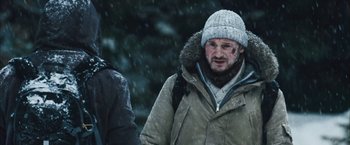 Movie still from “The Grey” (2011), directed by Joe Carnahan – A man wearing a jacket and hat in the snow; Close Up shot, Over the shoulder angle