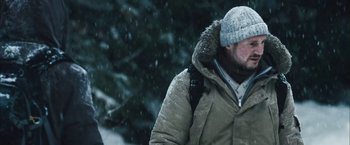 Movie still from “The Grey” (2011), directed by Joe Carnahan – A man with a beard wearing a winter coat and a hat; Close Up shot, Low angle