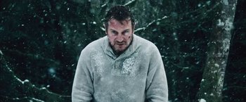 Movie still from “The Grey” (2011), directed by Joe Carnahan – A man in a white sweater standing in the snow; Medium shot, Over the shoulder angle