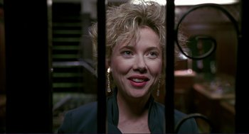 Movie still from “The Grifters” (1990), directed by Stephen Frears – A woman with blonde hair and blue eyes looking through a fence; Close Up shot, Over the shoulder angle