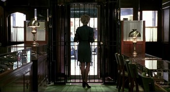 Movie still from “The Grifters” (1990), directed by Stephen Frears – A woman standing in front of an iron gate; Wide shot, Over the shoulder angle