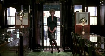Movie still from “The Grifters” (1990), directed by Stephen Frears – A woman standing in front of a bar holding a baseball bat; Wide shot, Low angle