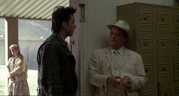 Movie still from “The Grifters” (1990), directed by Stephen Frears – A man in a suit and a hat talking to another man in a hat; Medium shot, Over the shoulder angle