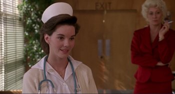 Movie still from “The Grifters” (1990), directed by Stephen Frears – A woman in a nurse's uniform with a stethoscope around her neck; Close Up shot, Over the shoulder angle