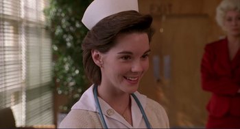 Movie still from “The Grifters” (1990), directed by Stephen Frears – A woman wearing a nurse's uniform and smiling for the camera; Close Up shot, Low angle