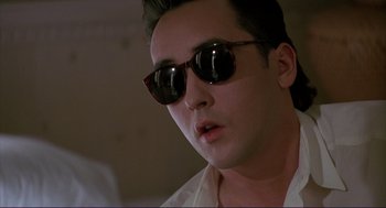 Movie still from “The Grifters” (1990), directed by Stephen Frears – A person wearing sunglasses; Close Up shot, Low angle