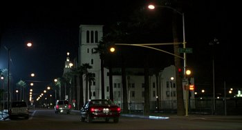 Movie still from “The Grifters” (1990), directed by Stephen Frears – A red car driving down a street at night; Extreme Wide shot, Low angle