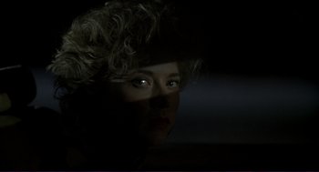 Movie still from “The Grifters” (1990), directed by Stephen Frears – A woman with curly blonde hair is looking at the camera; Close Up shot, Over the shoulder angle