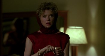 Movie still from “The Grifters” (1990), directed by Stephen Frears – A woman in a red dress holding a camera in a room; Close Up shot, Over the shoulder angle