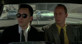 Movie still from “The Grifters” (1990), directed by Stephen Frears – Two men in suits and ties sitting in the back of a car; Close Up shot, Low angle