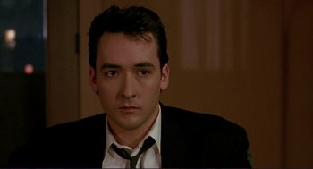 Movie still from “The Grifters” (1990), directed by Stephen Frears – A person wearing a suit and tie; Close Up shot, Low angle