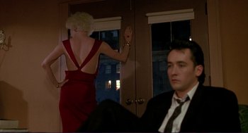 Movie still from “The Grifters” (1990), directed by Stephen Frears – A woman in a red dress standing next to a man in a black suit; Medium shot, Low angle